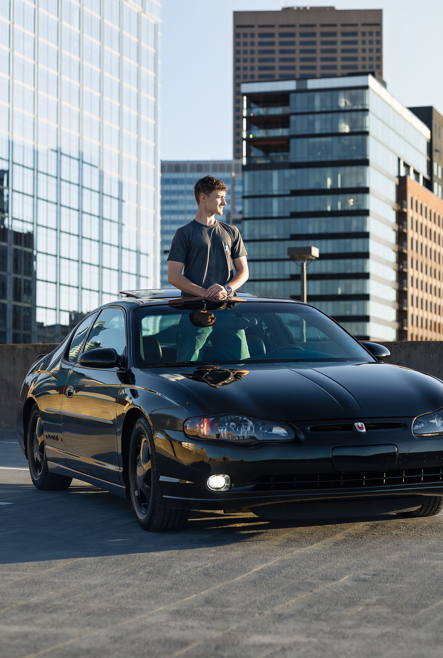 Young man standing out of a sunroof with a city landscape background