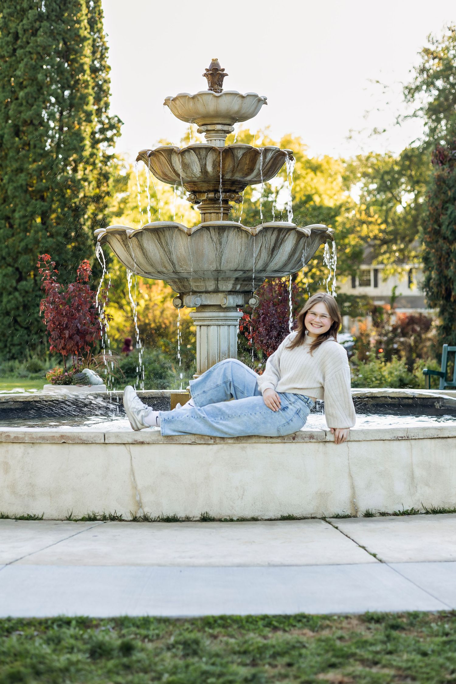 Girl leaning back on water fountain with legs up