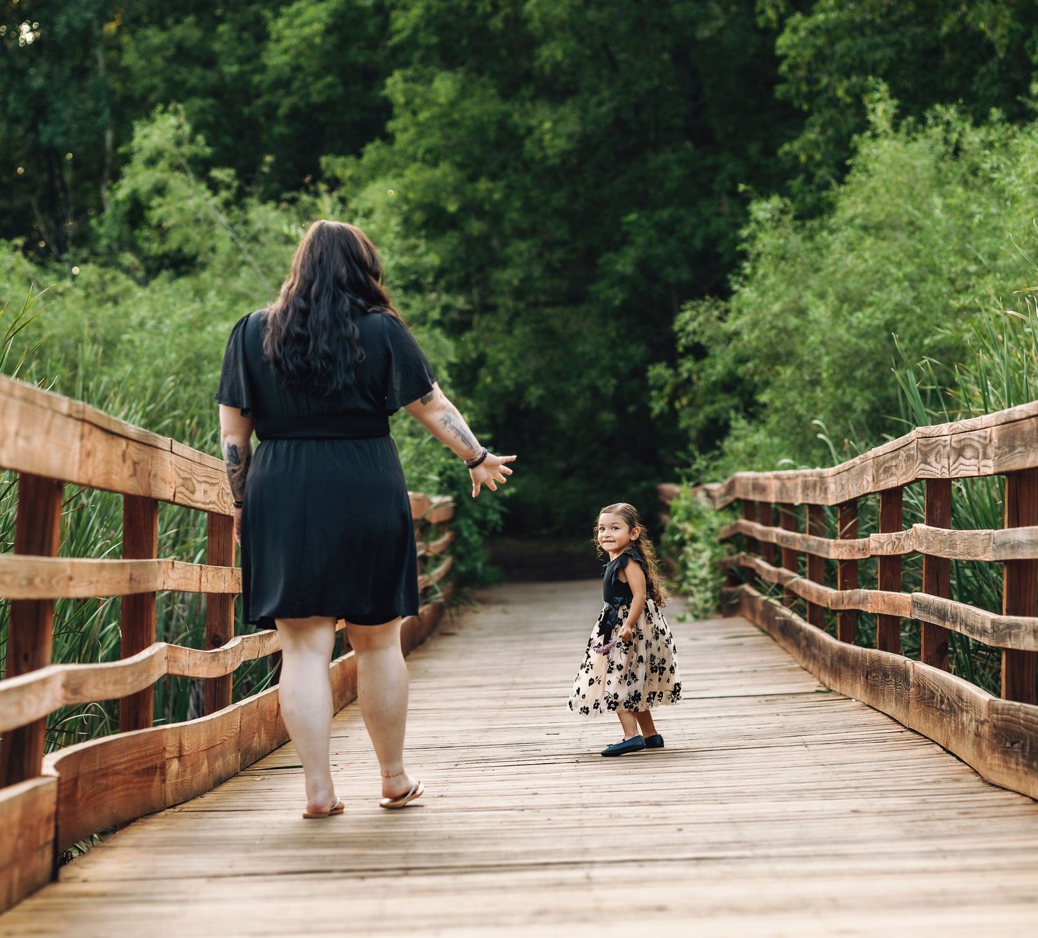 Mother holding her hand out for daughter while walking across a bridge