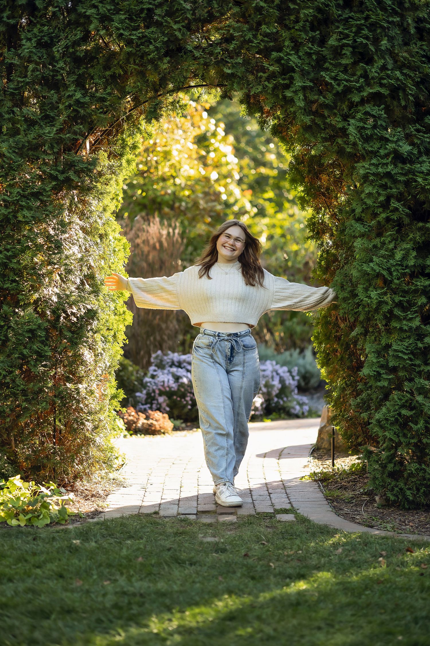 Senior girl walking through the arch with arms out