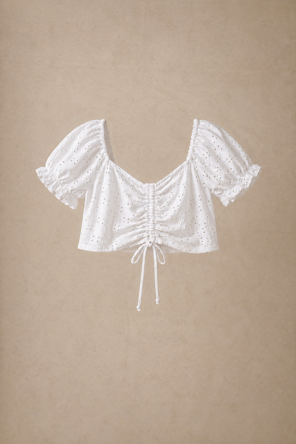 White eyelet lace crop top with puff sleeves, sweetheart neckline, and ruched drawstring front detail.