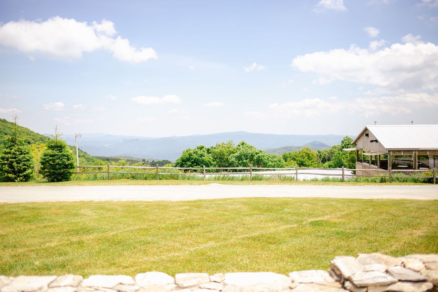 Scenic mountain view from wedding venue with green lawn and rustic building.