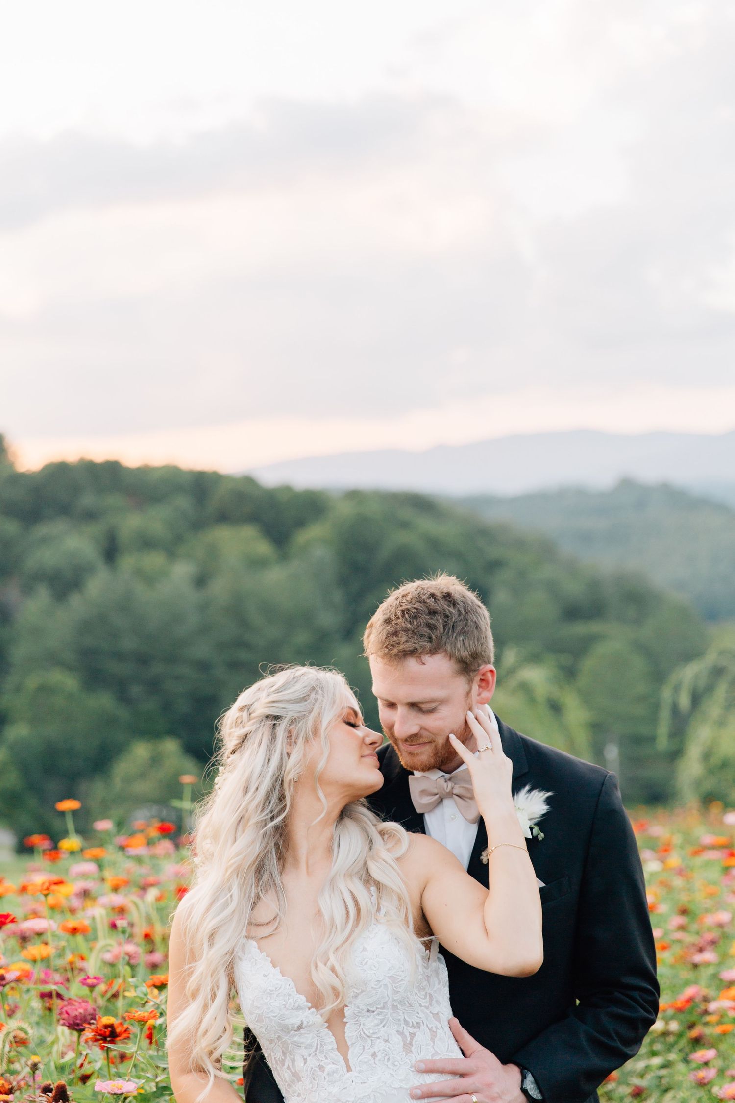 Intimate wedding portrait in a blooming flower field with mountain views.