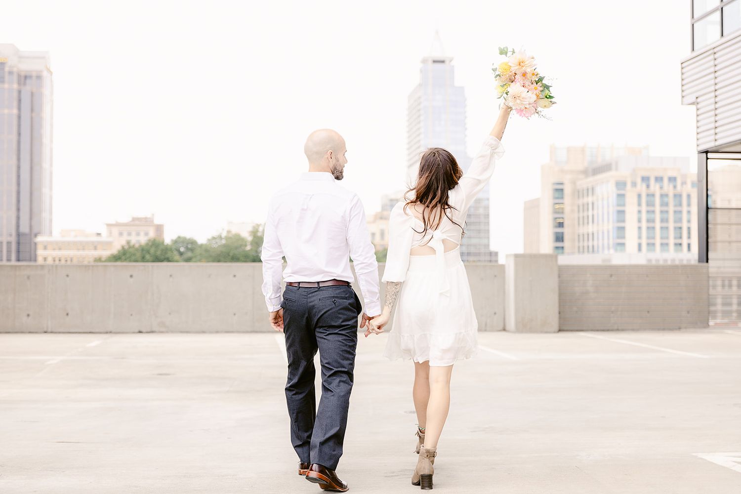 A bride and groom share a romantic moment on a rooftop with city buildings in the background.