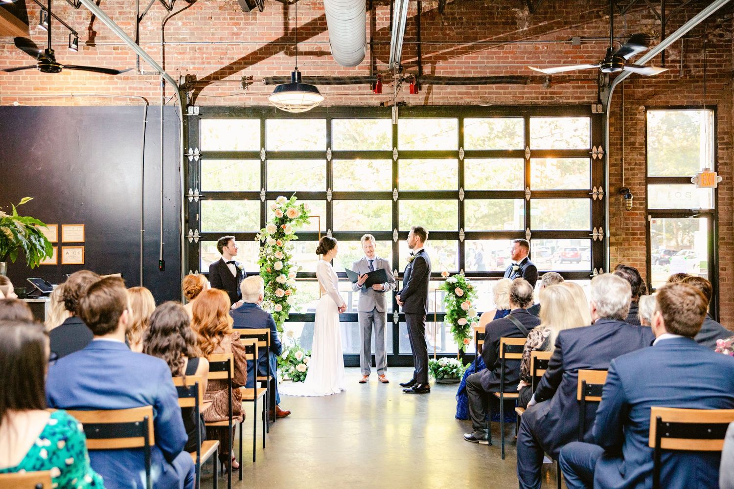 Modern industrial office space with exposed brick walls, wooden beams, and large windows creating a bright workspace.