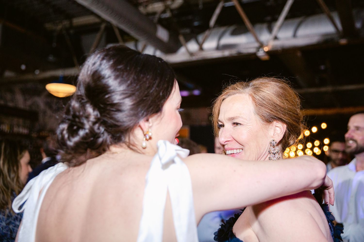 Joyful celebration at a wedding reception with guests dancing under warm lighting.