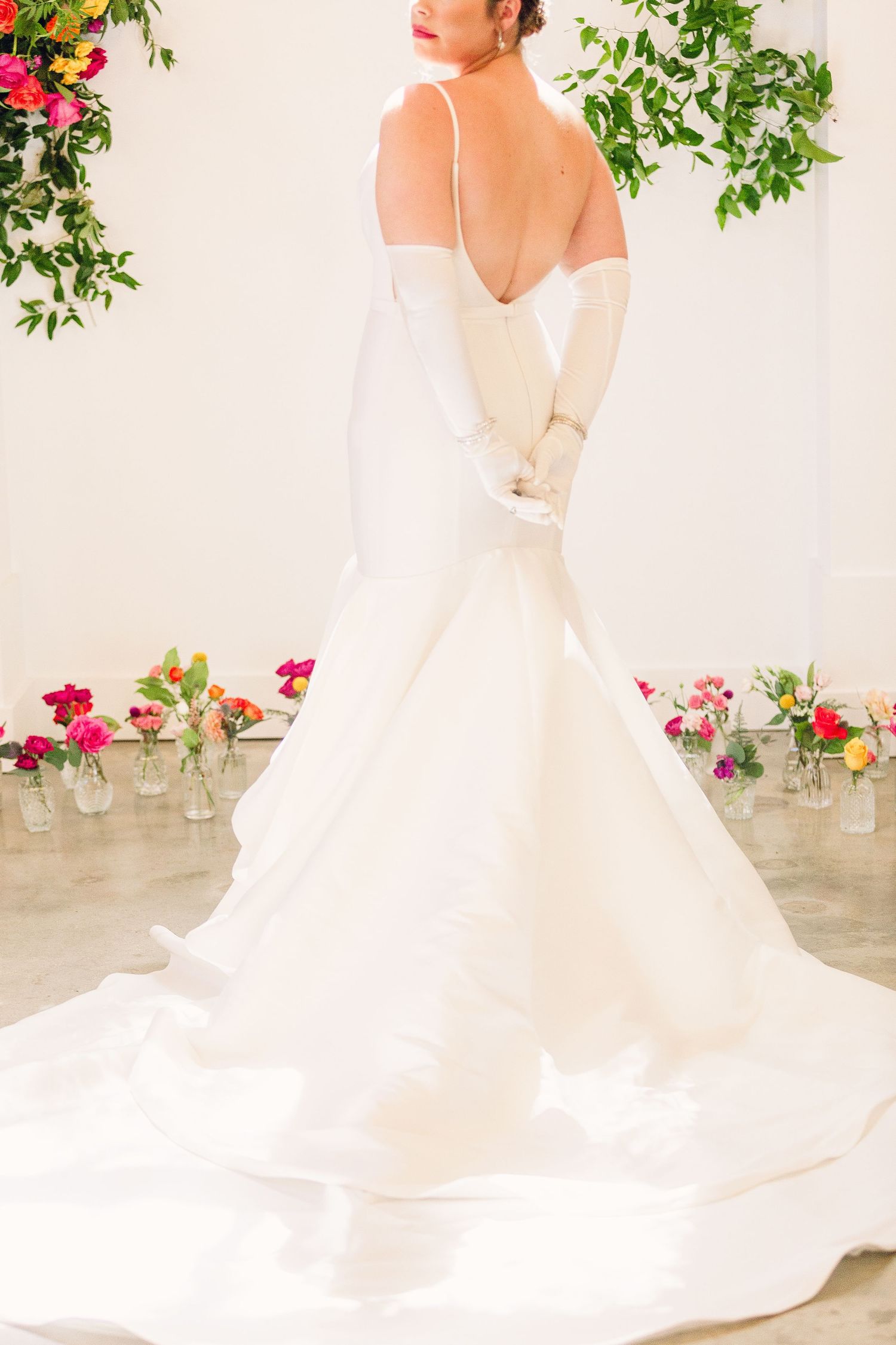 Wedding gown with elegant train photographed against floral backdrop.
