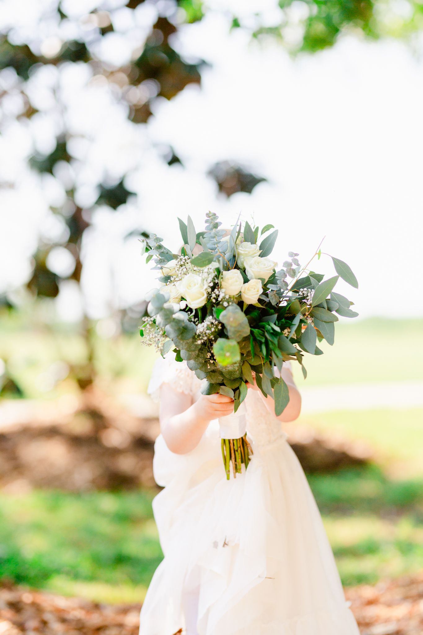 Elegant white floral bouquet with eucalyptus leaves arranged in a glass vase for a wedding celebration.