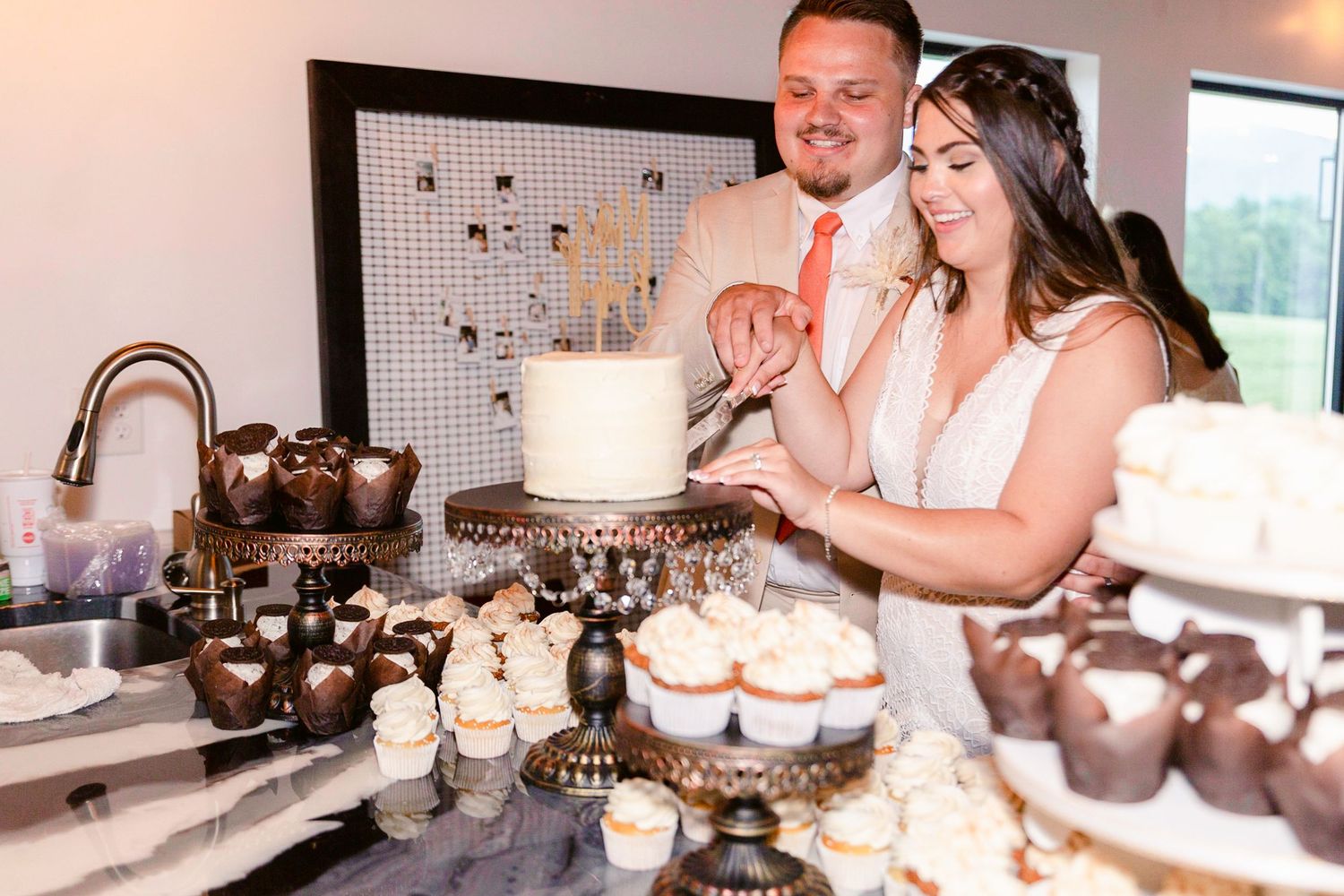 A couple poses in a kitchen with faucets and plumbing fixtures displayed in a showroom setting.