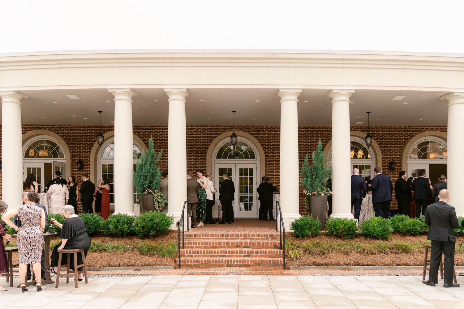 A panoramic view of a white colonial-style building entrance with arched windows and columns along the facade.