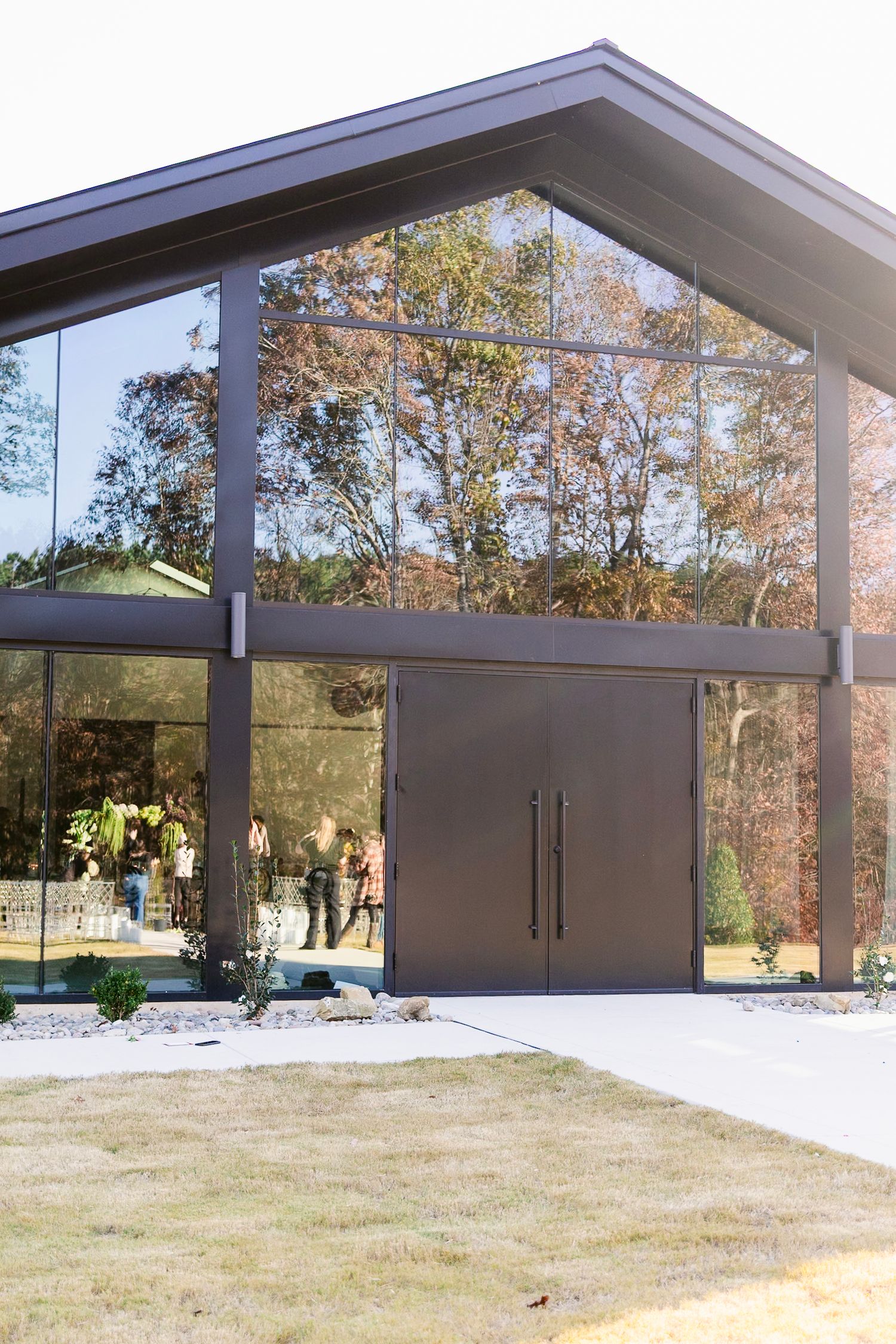 Covered outdoor pavilion with dark metal posts and doors overlooking a grassy landscape.