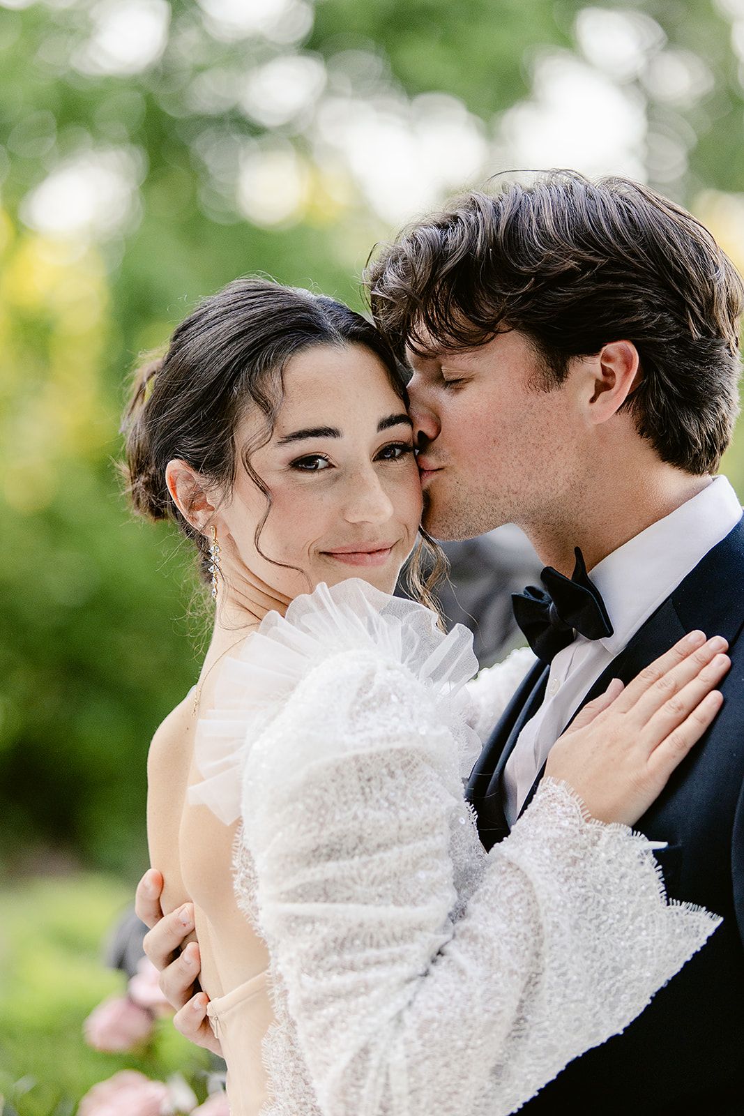 A romantic wedding couple shares intimate kisses in a series of outdoor portraits with natural greenery in background.