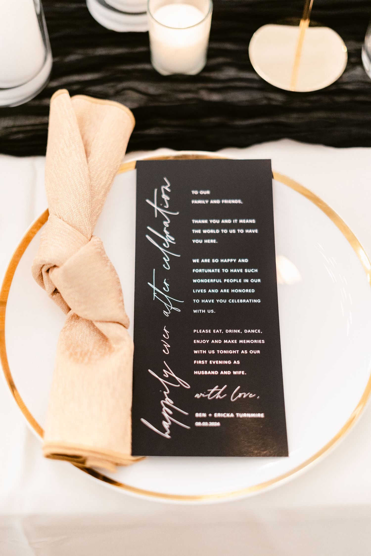 Elegant black wedding menu cards with white calligraphy text displayed on cream colored plates with gold trim.