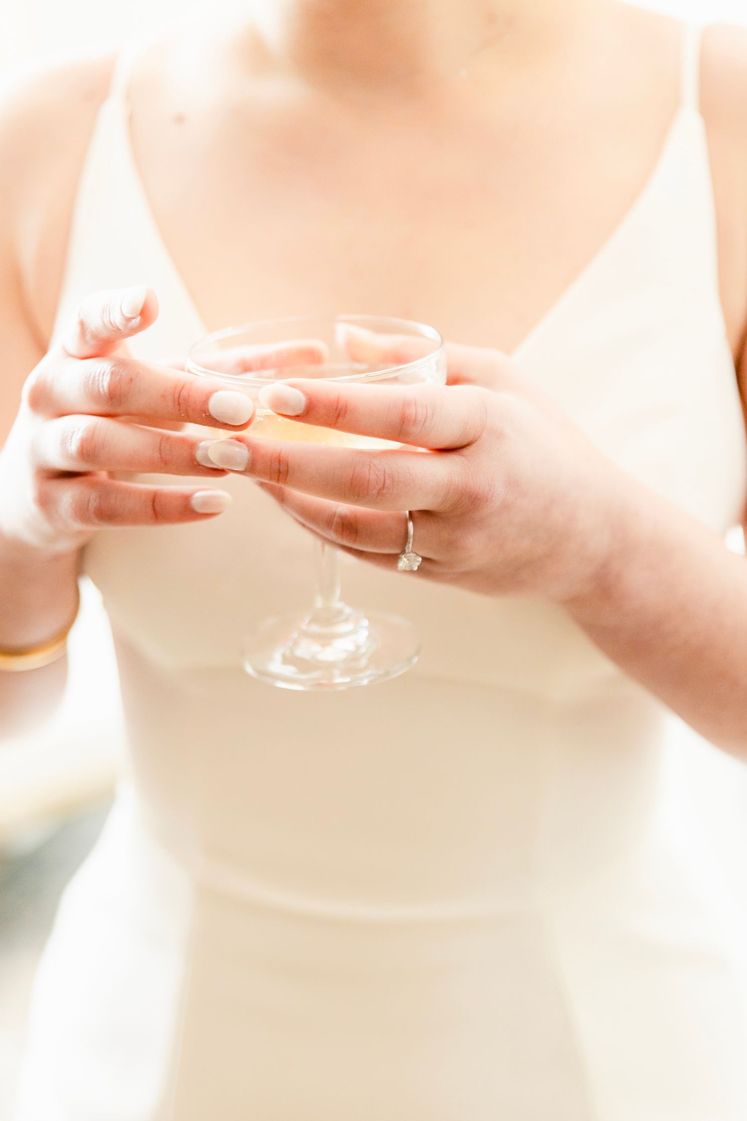 Close-up sequence of hands holding a delicate champagne glass in soft lighting.