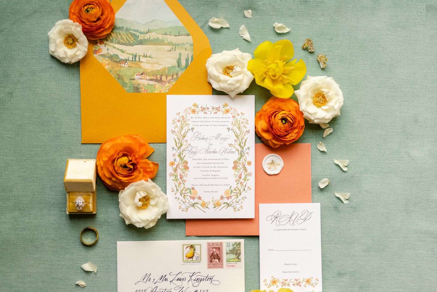 Elegant wedding invitations and floral arrangements in orange, yellow and white on a sage green textured background.
