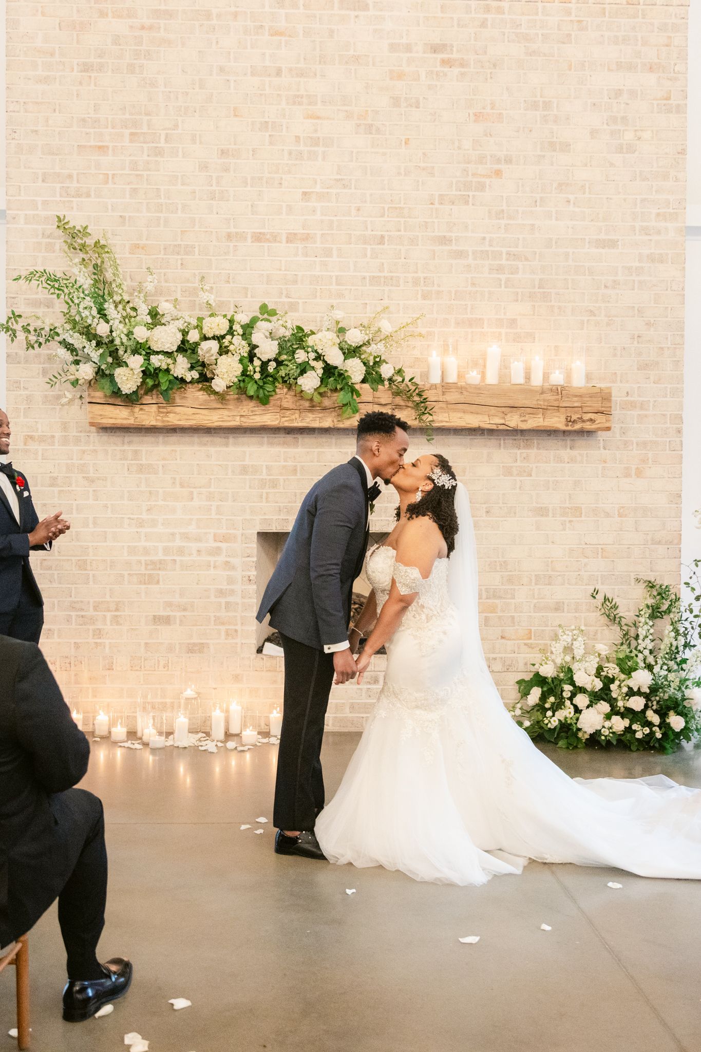 Romantic wedding ceremony in a modern brick venue decorated with white flowers and candles.