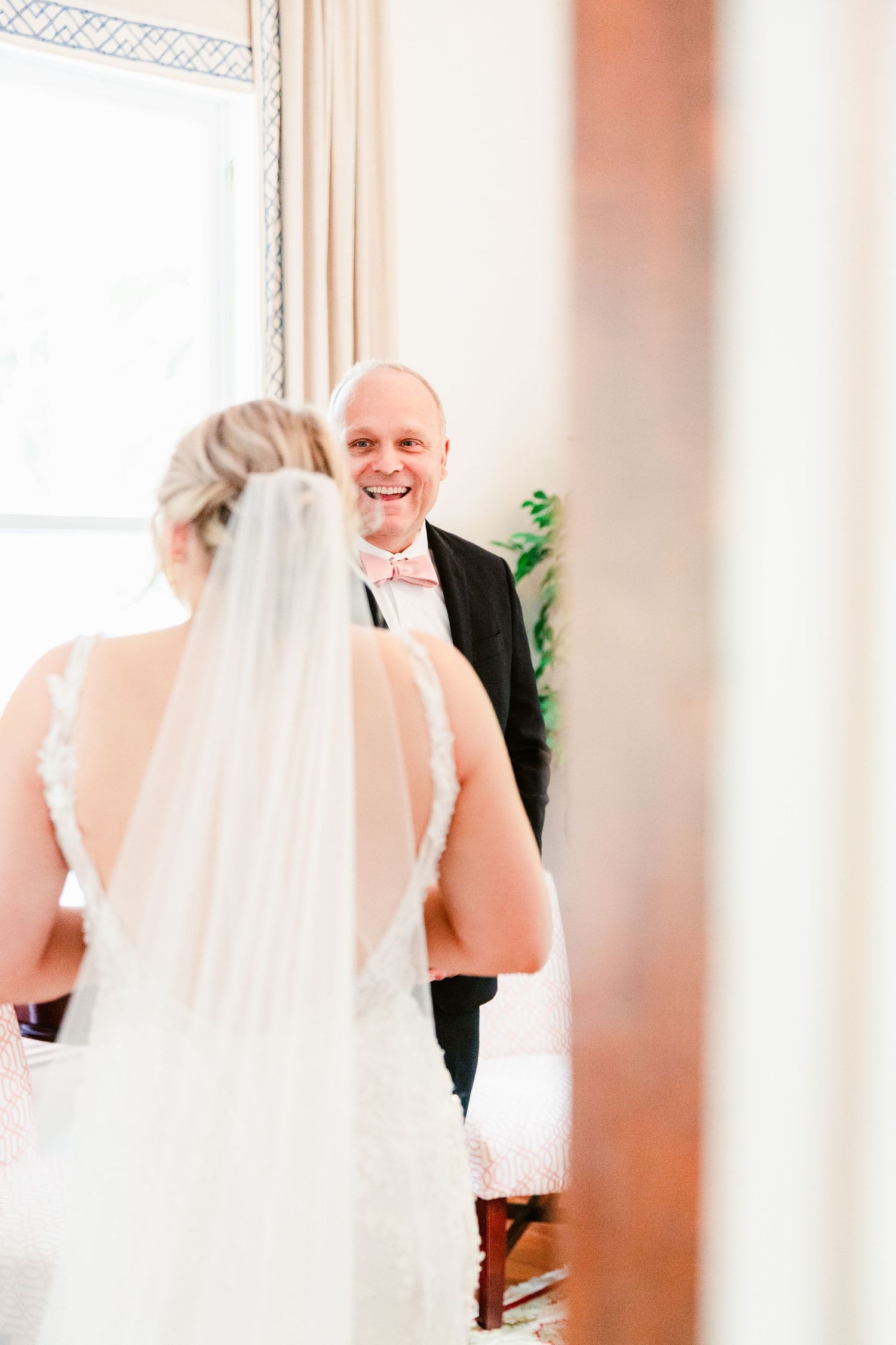 A bride in a white wedding gown and veil shares a joyful moment during the wedding ceremony.