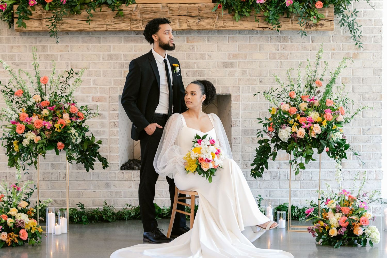 Elegant wedding venue decorated with vibrant floral arrangements against white brick walls and natural greenery.