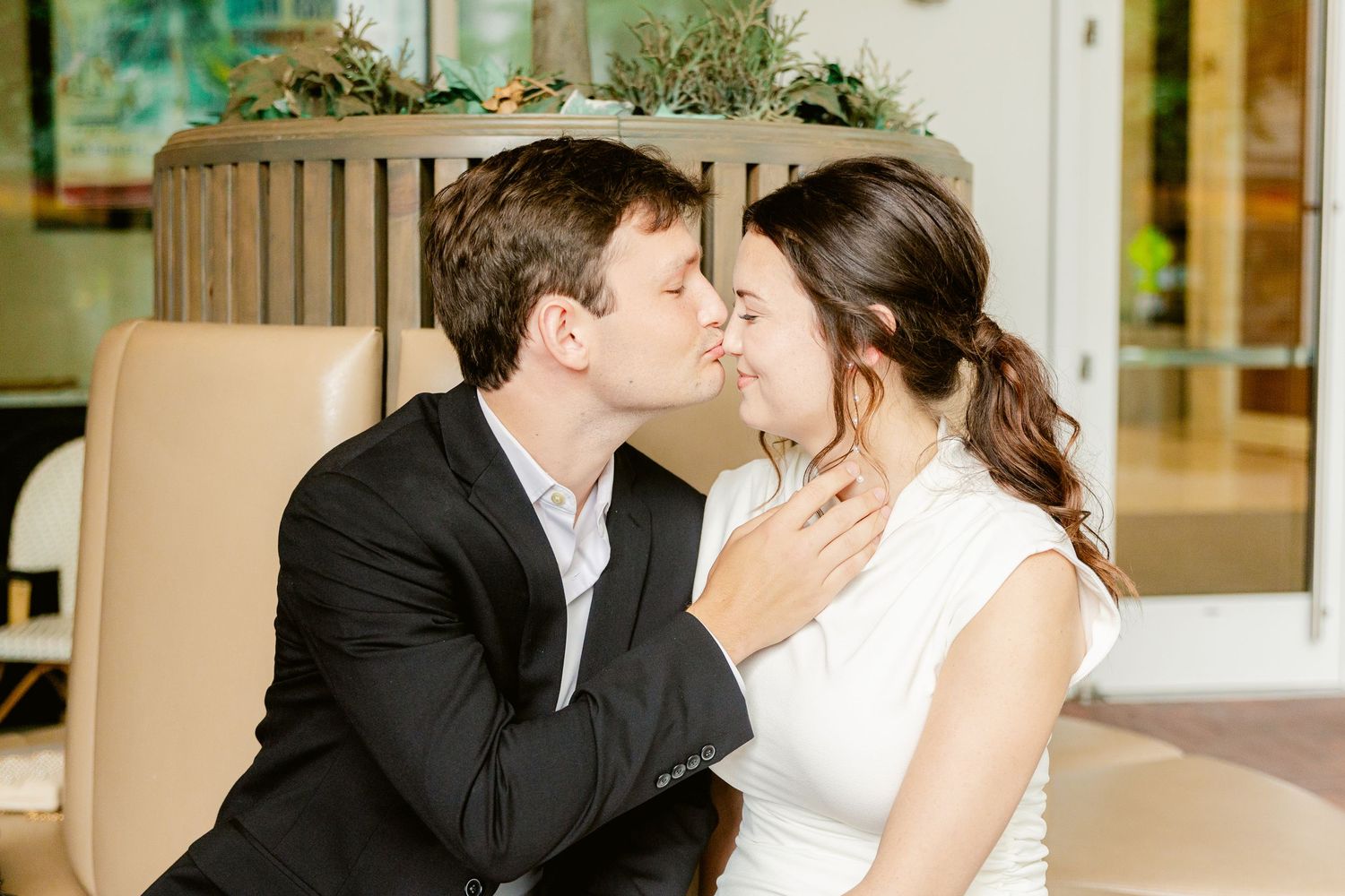 A romantic couple shares a tender kiss while sitting together at an upscale venue.