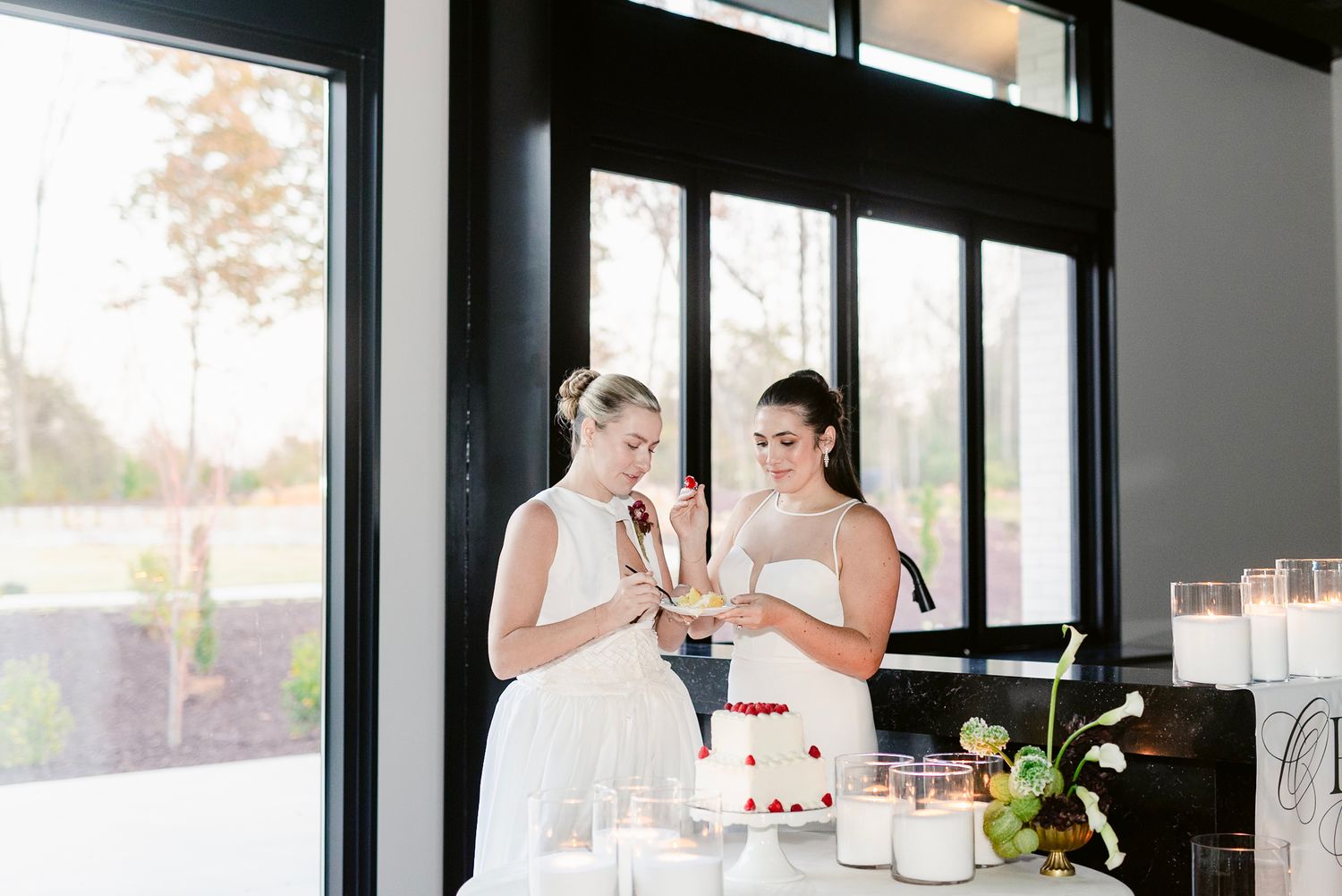 Two people in elegant attire share a toast with champagne glasses during a celebration at a bright indoor venue.