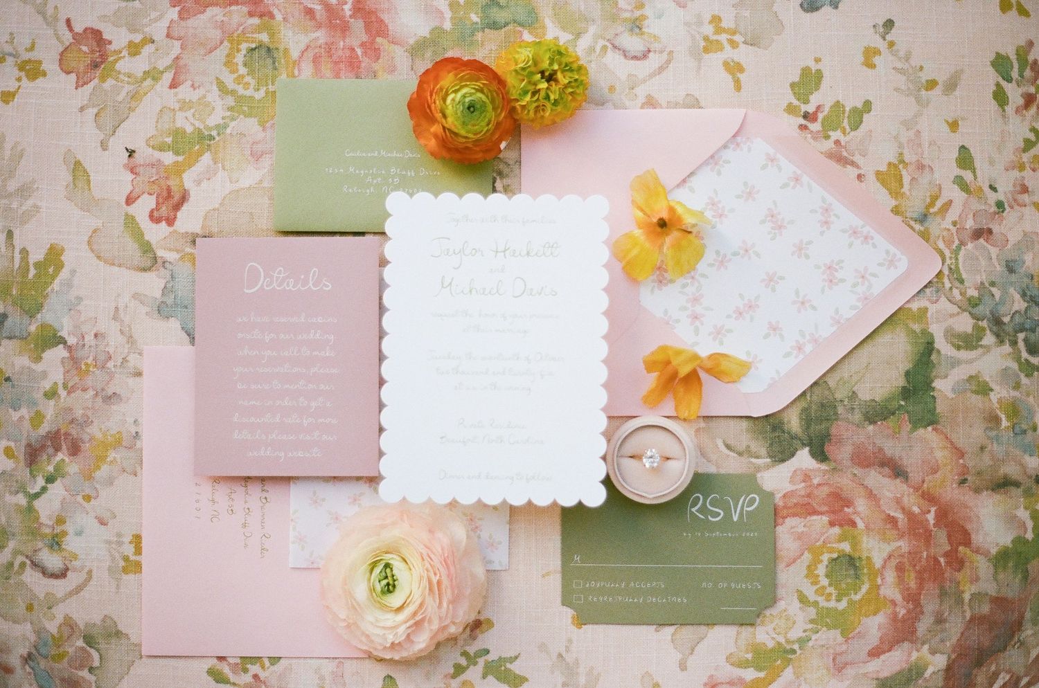 Vintage floral stationery arrangement with pink and white papers decorated with orange and yellow ranunculus flowers.