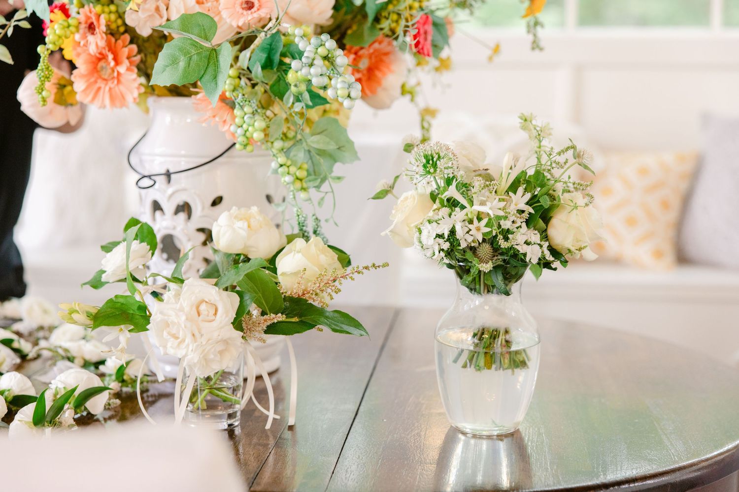 Elegant wedding table settings with blush pink floral centerpieces and crystal glassware in a light-filled reception space.