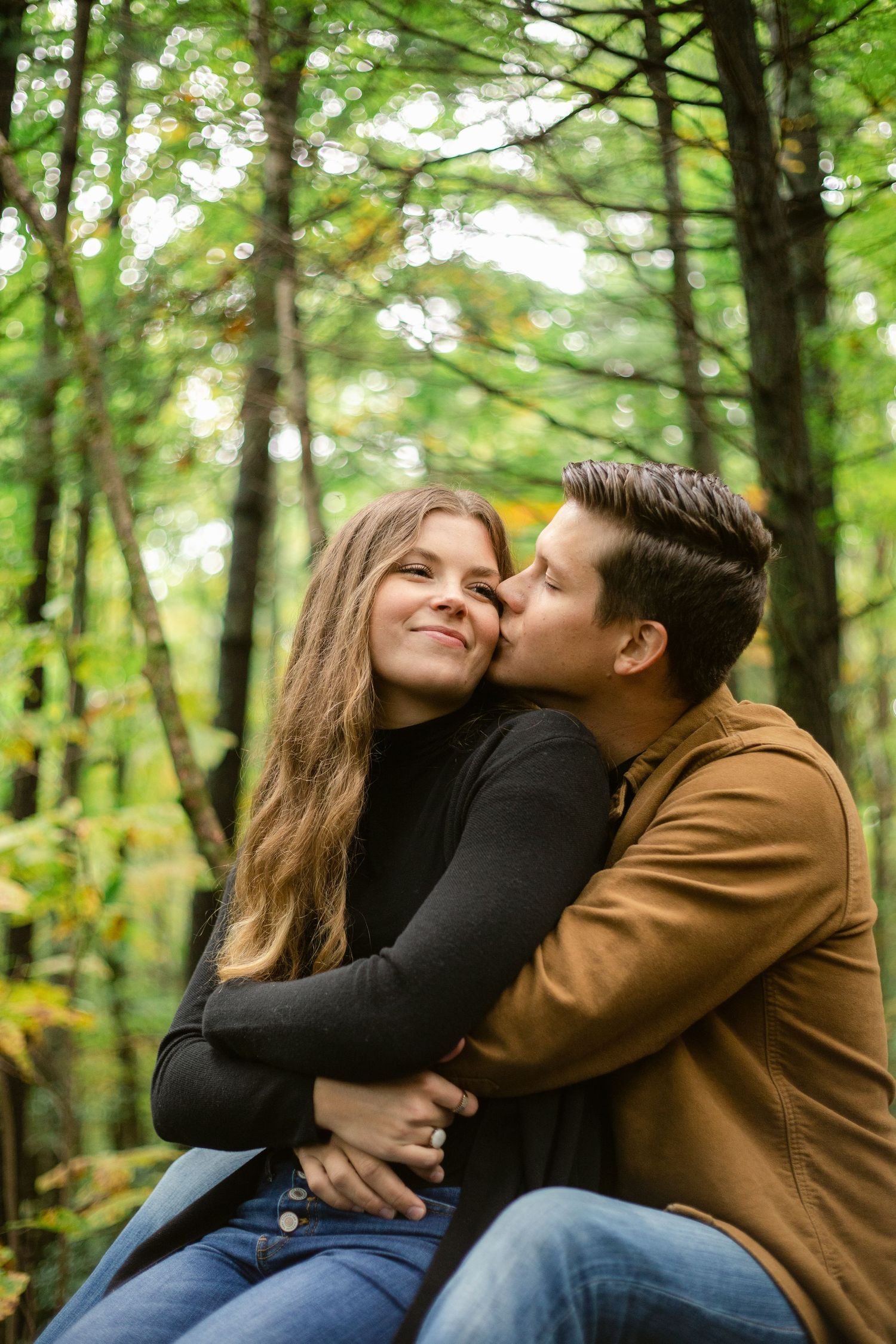 Tender moment between couple embracing in a lush green forest setting.