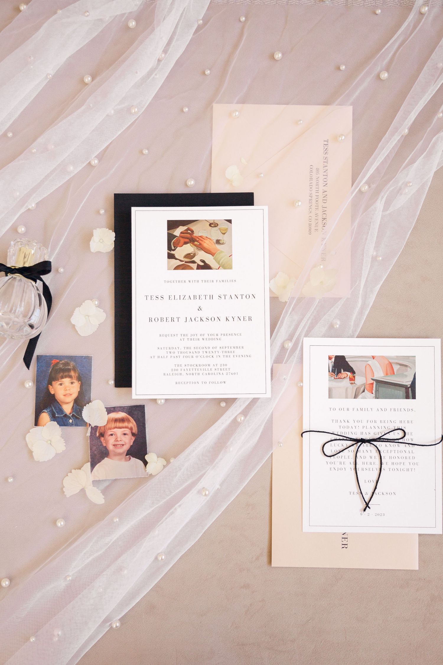 Wedding invitation suite displayed on delicate tulle fabric with pearl details.