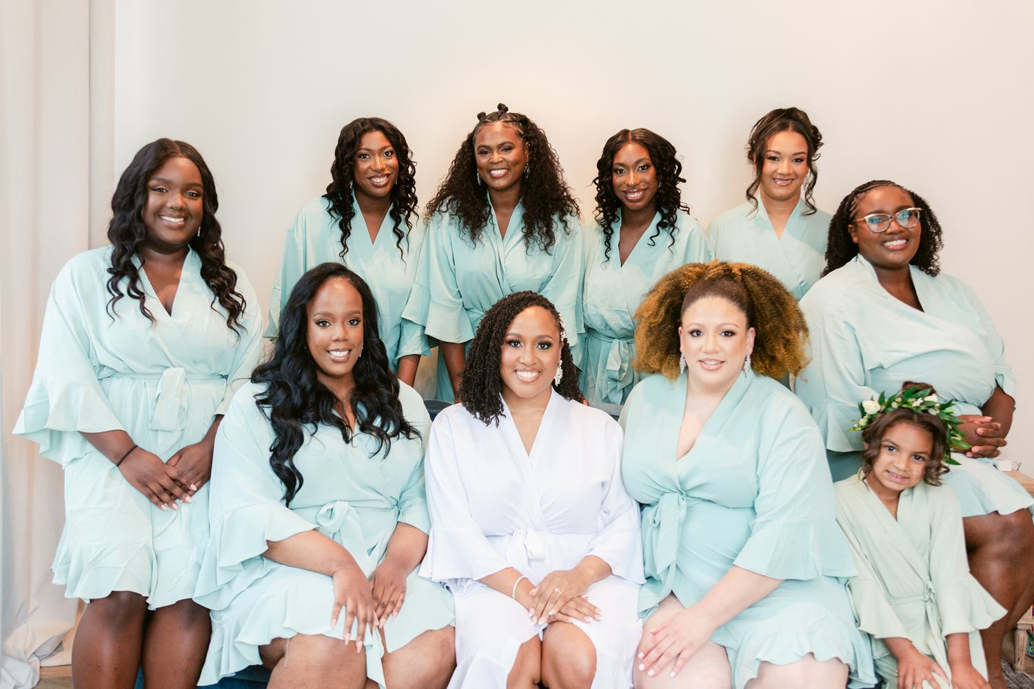 Group wearing matching mint green robes pose together for formal bridal party portrait.