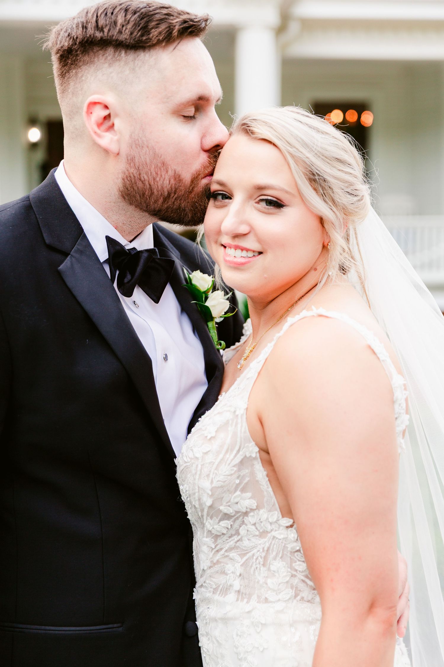 A tender wedding moment captured between newlyweds as they share an intimate pose in formal attire.