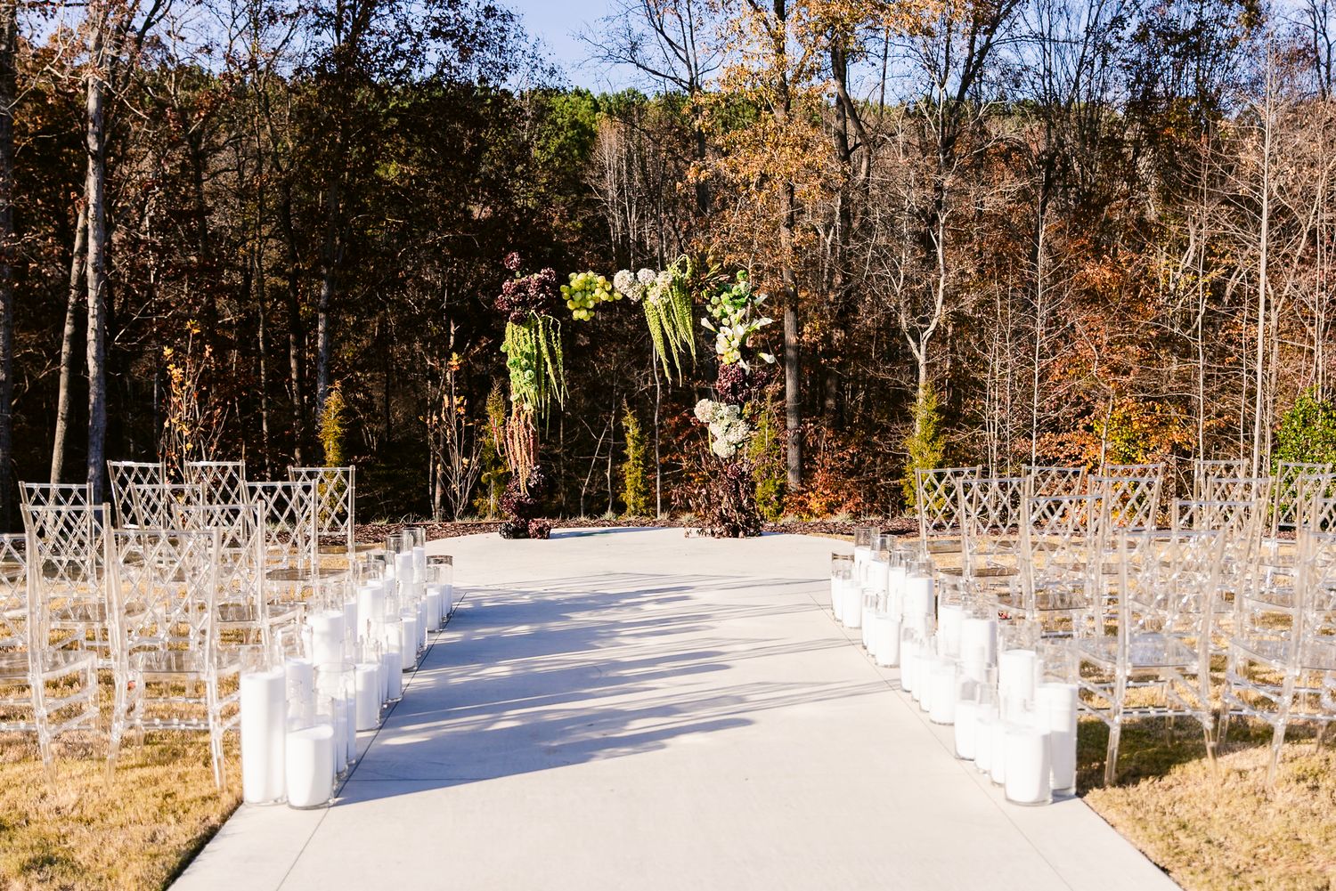 A long panoramic view of a white fence along a winding rural path surrounded by autumn trees and foliage.