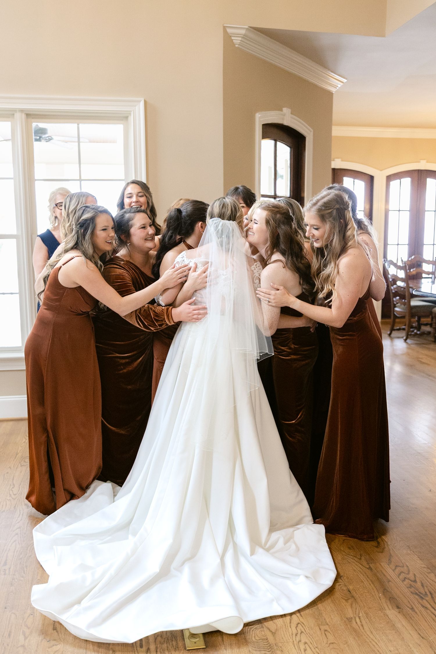 Bride in white wedding gown embraces bridesmaids wearing brown dresses in a sequence of emotional group photos.