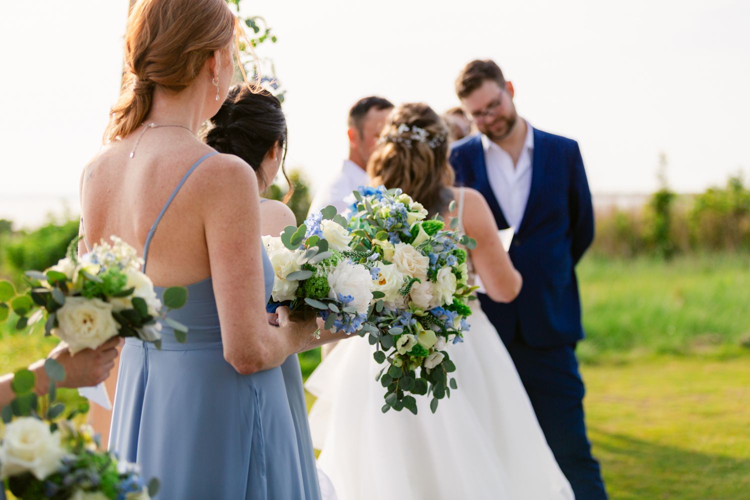 A romantic outdoor wedding ceremony with a couple embracing in a sun-drenched field at sunset.