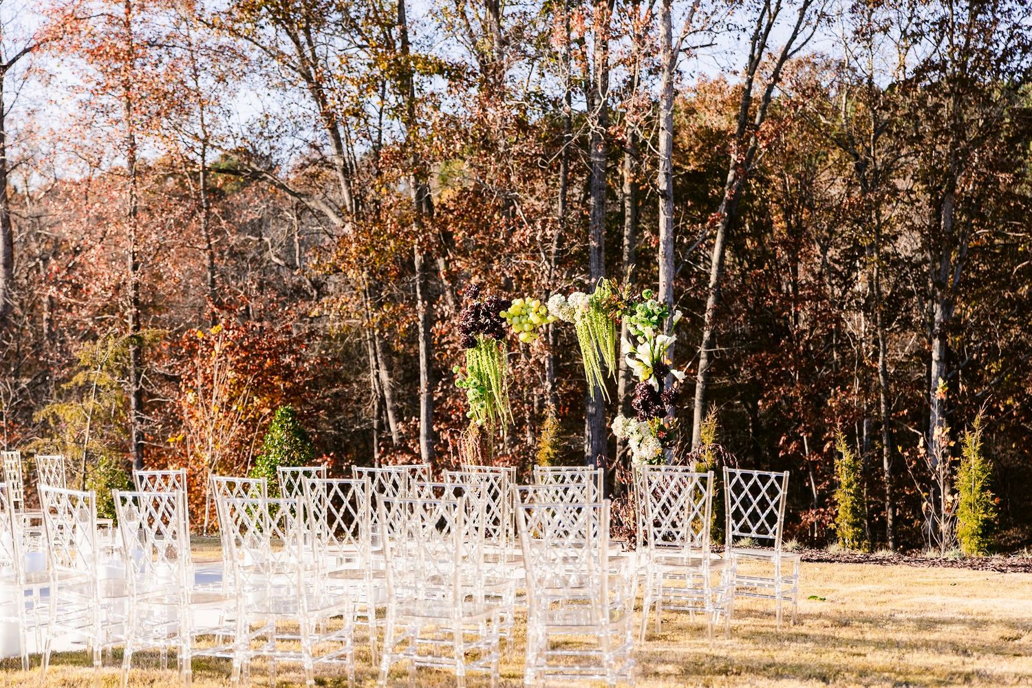 A panoramic view of a white wooden fence stretching along a tree-lined path with autumn foliage.