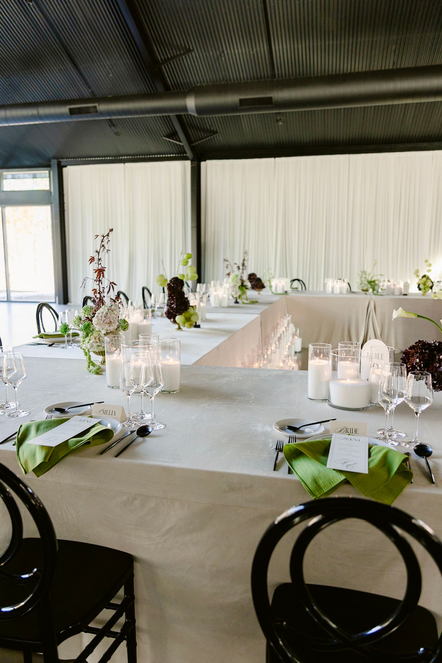 Modern table settings with white linens and black plates arranged in rows for an elegant dining event.