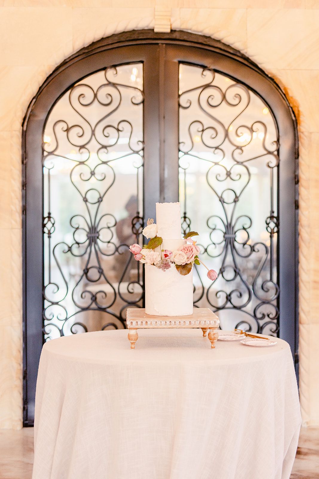 Ornate wrought iron arched windows with decorative scrollwork and white tablecloths beneath.