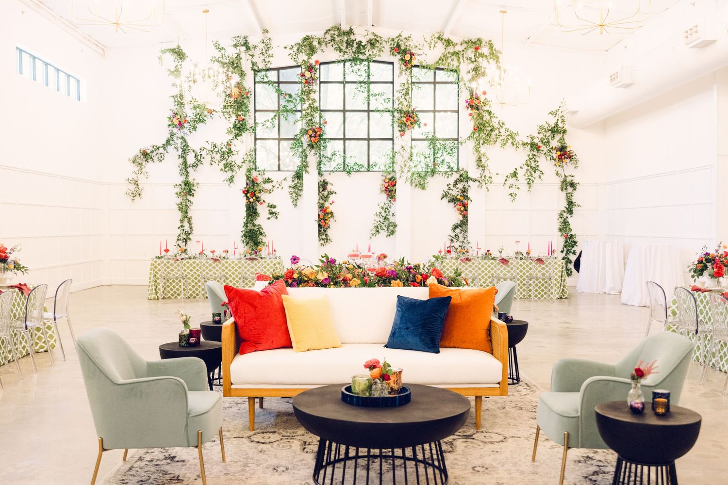 Stylish lounge area with white sofa, green chairs and floral window arrangements.