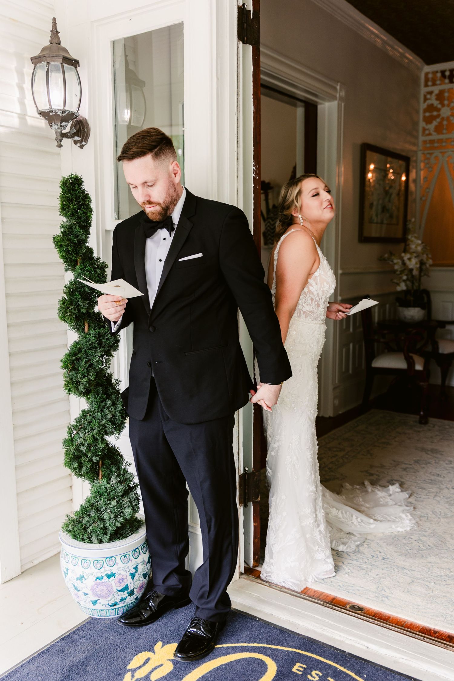 A couple reads private notes before their first look on their wedding day, separated by a doorway.