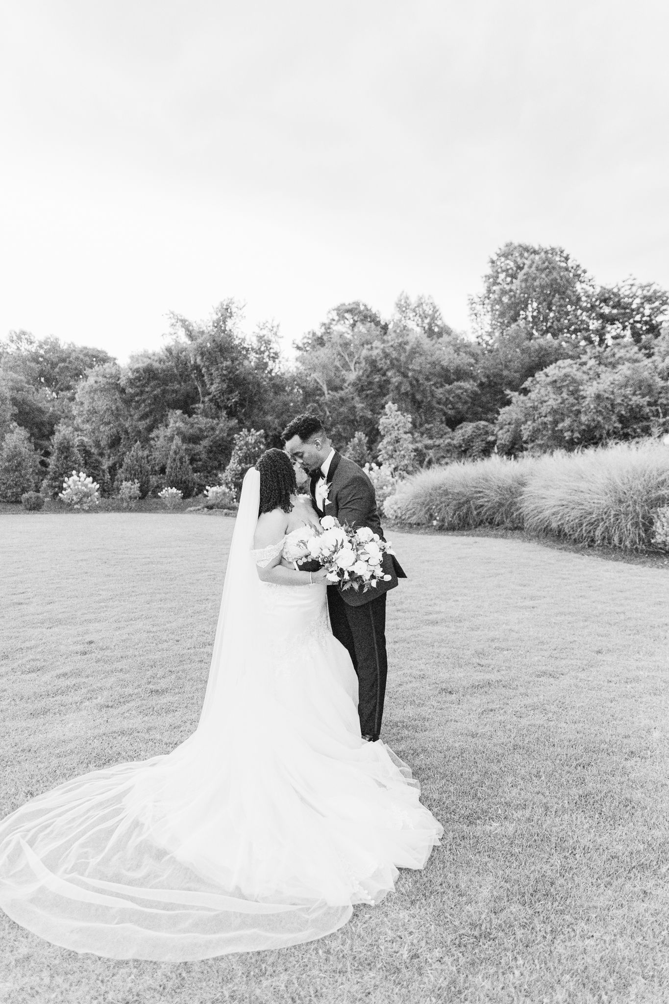 A romantic black and white wedding photo sequence showing a couple walking together across a grassy field.