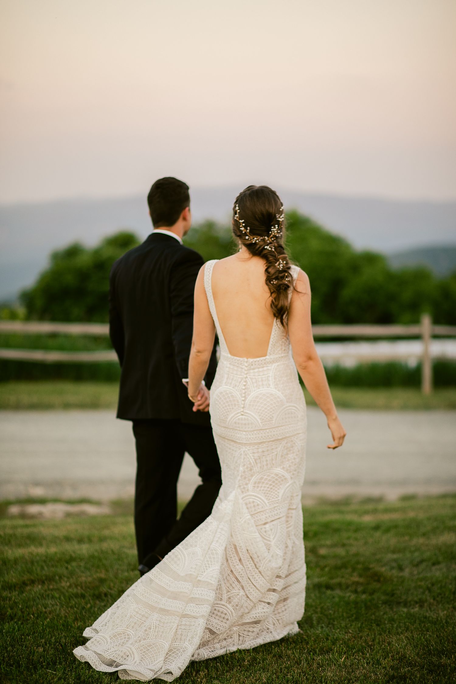 Back view of couple holding hands while looking at mountain landscape in evening light.