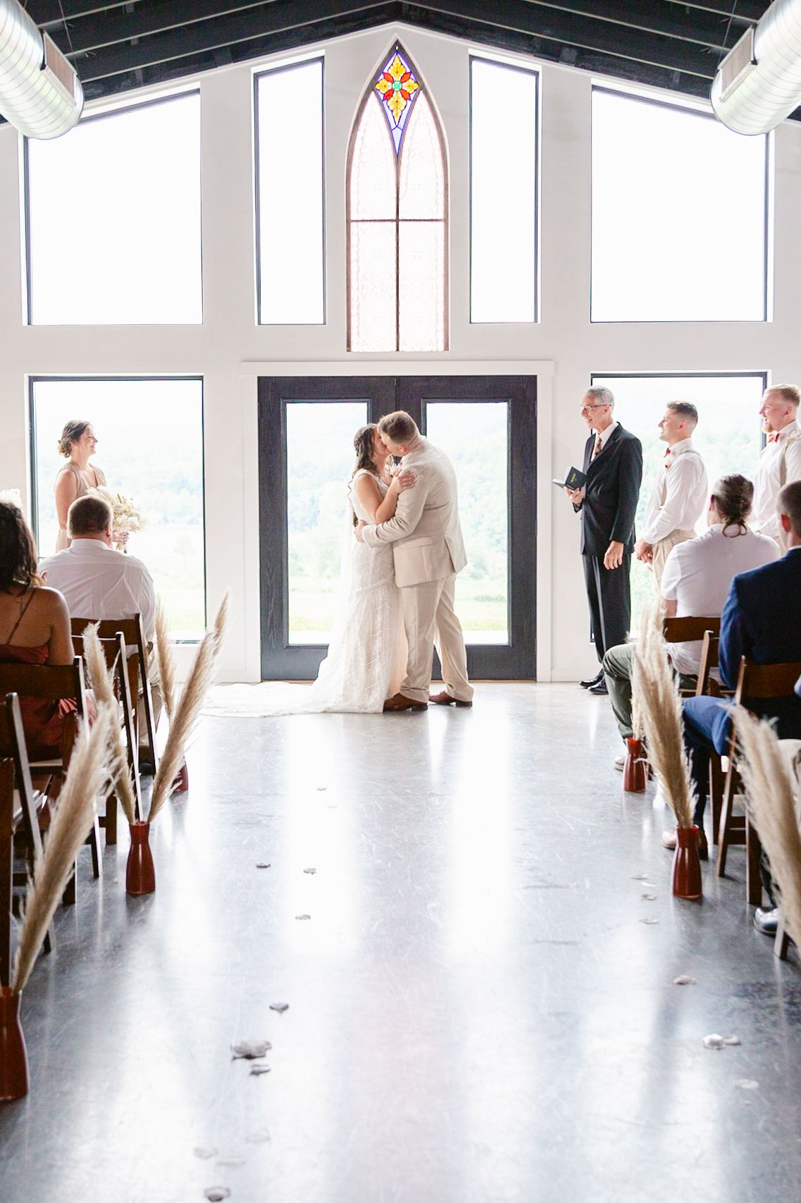 A minimalist white chapel interior with guests seated in rows for a wedding ceremony.