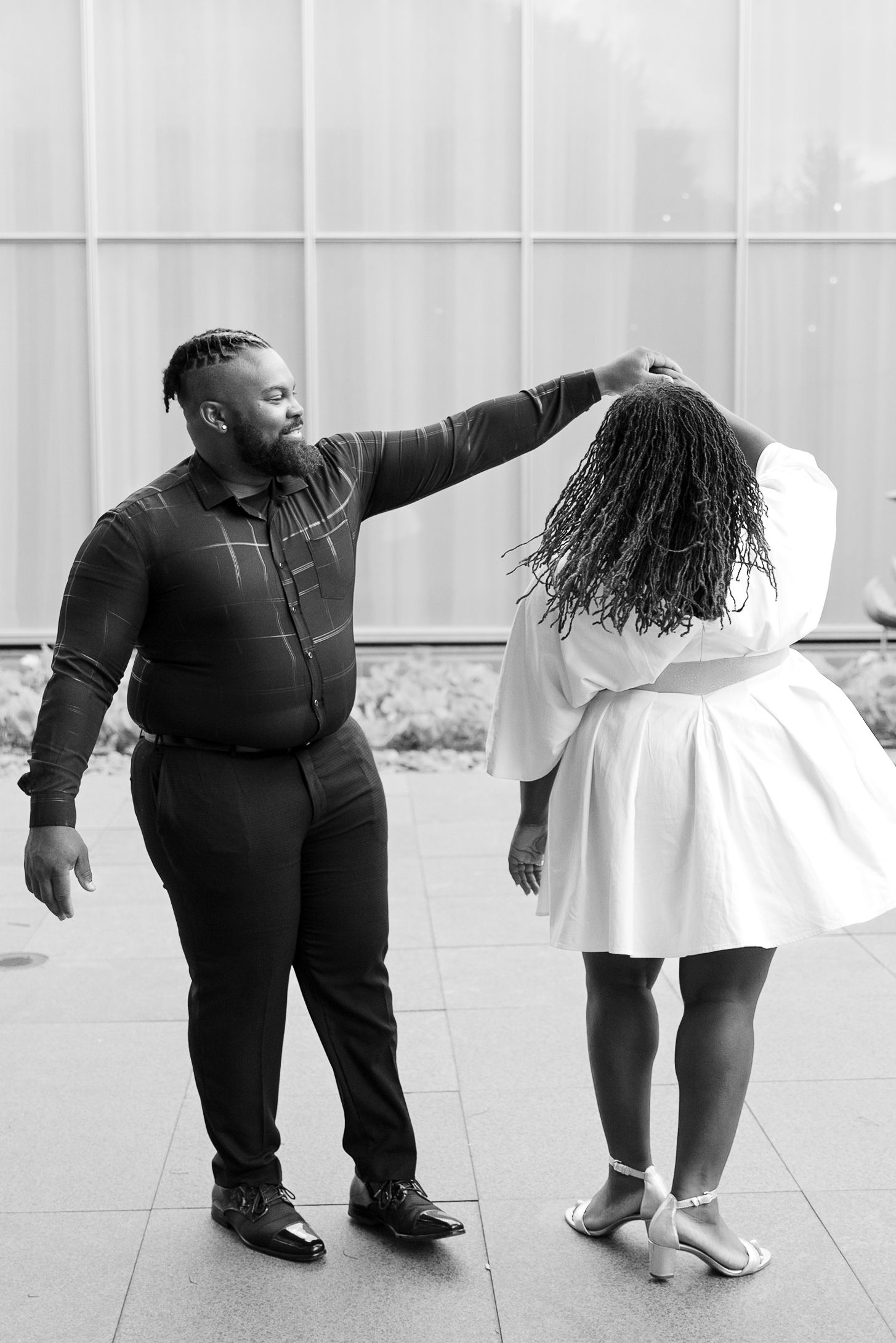 Black and white artistic engagement photo series showing couple in playful poses on tiled floor.