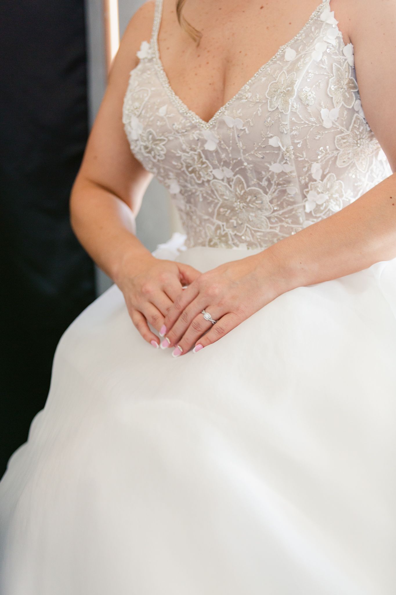Close-up details of a white lace wedding dress bodice with delicate beading and embellishments.