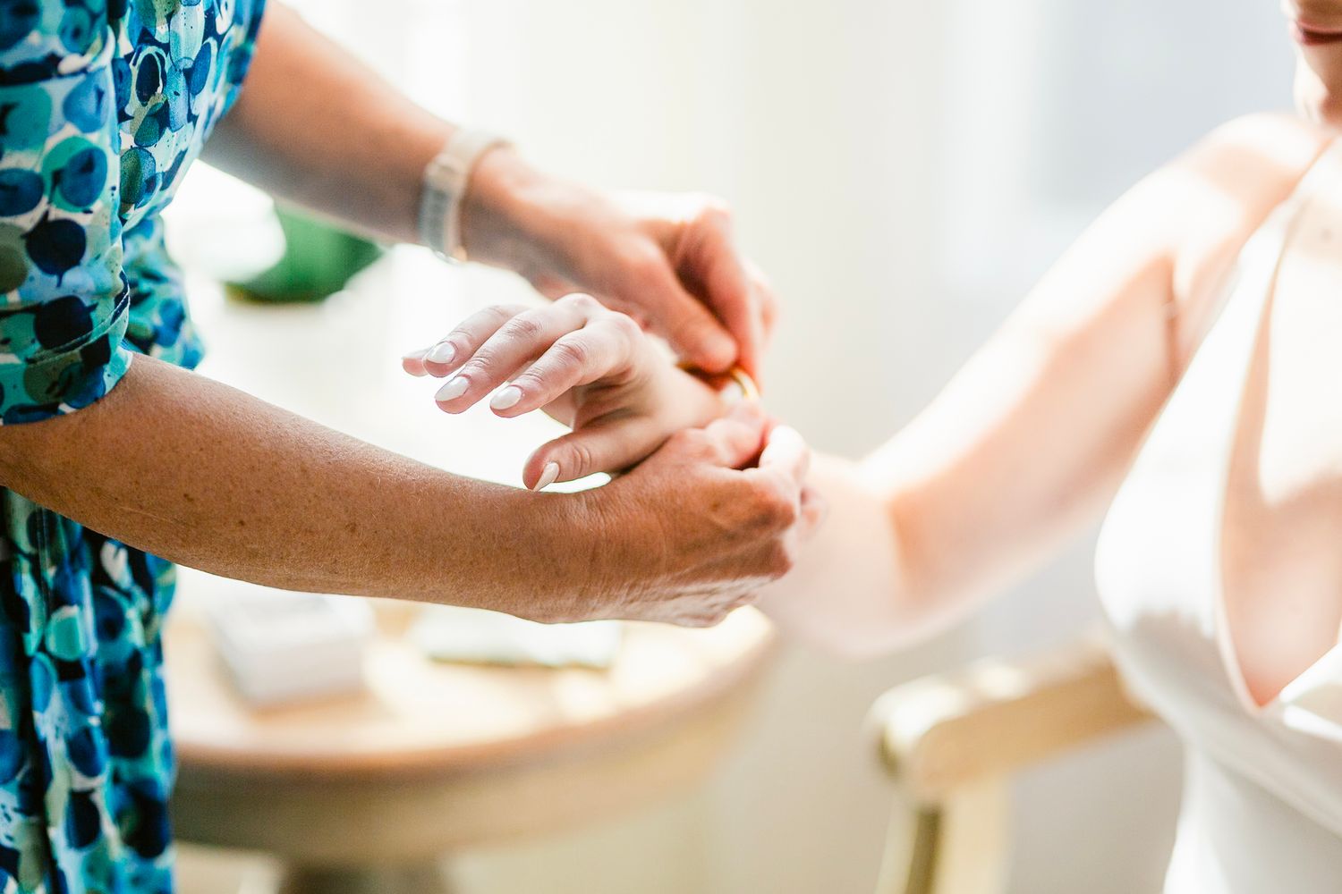 A close-up of hands comfortingly clasped together in a caring gesture against a soft, bright background.