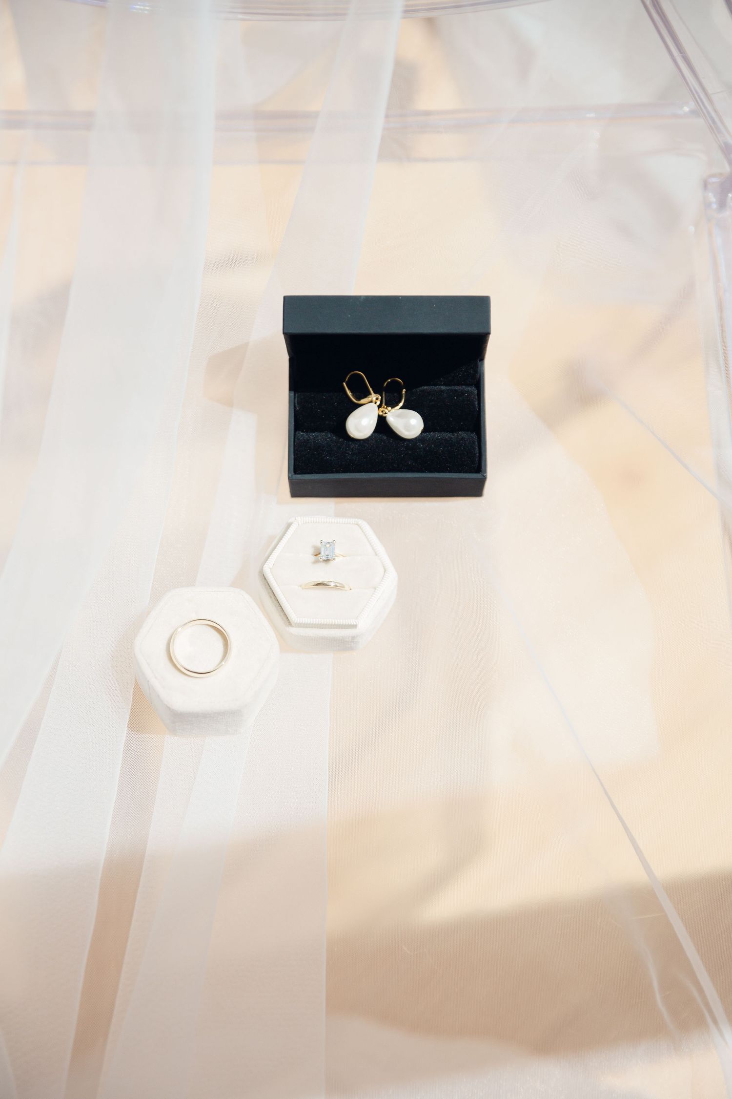 Wedding rings and jewelry boxes arranged on white fabric surface.