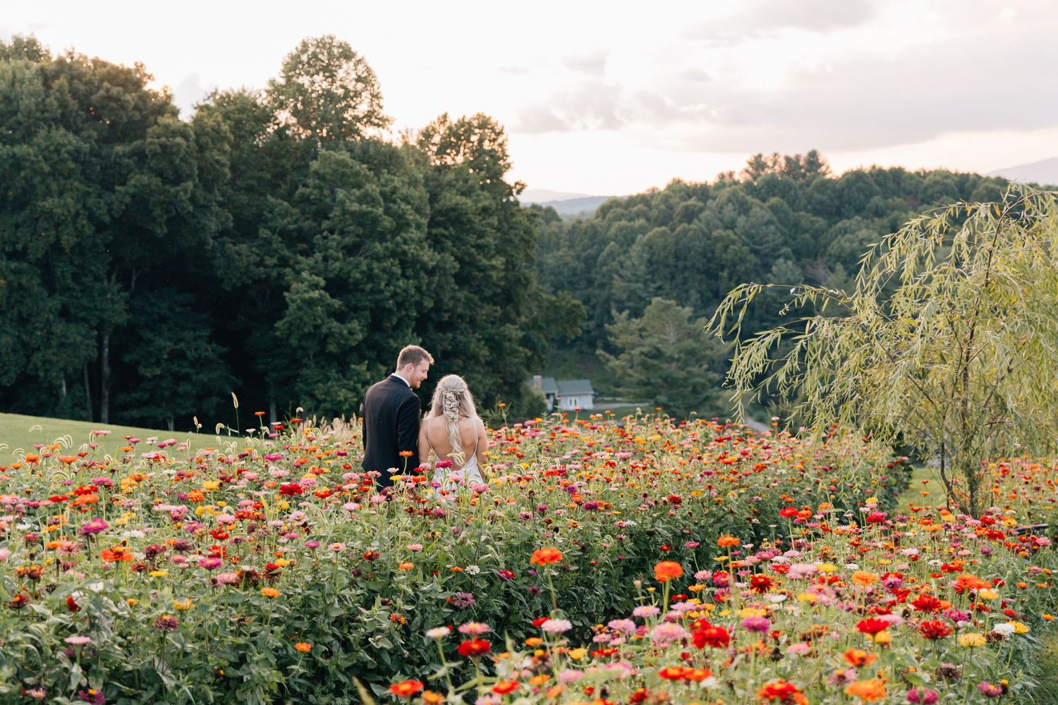 Newlyweds standing together in a colorful wildflower meadow during golden hour.