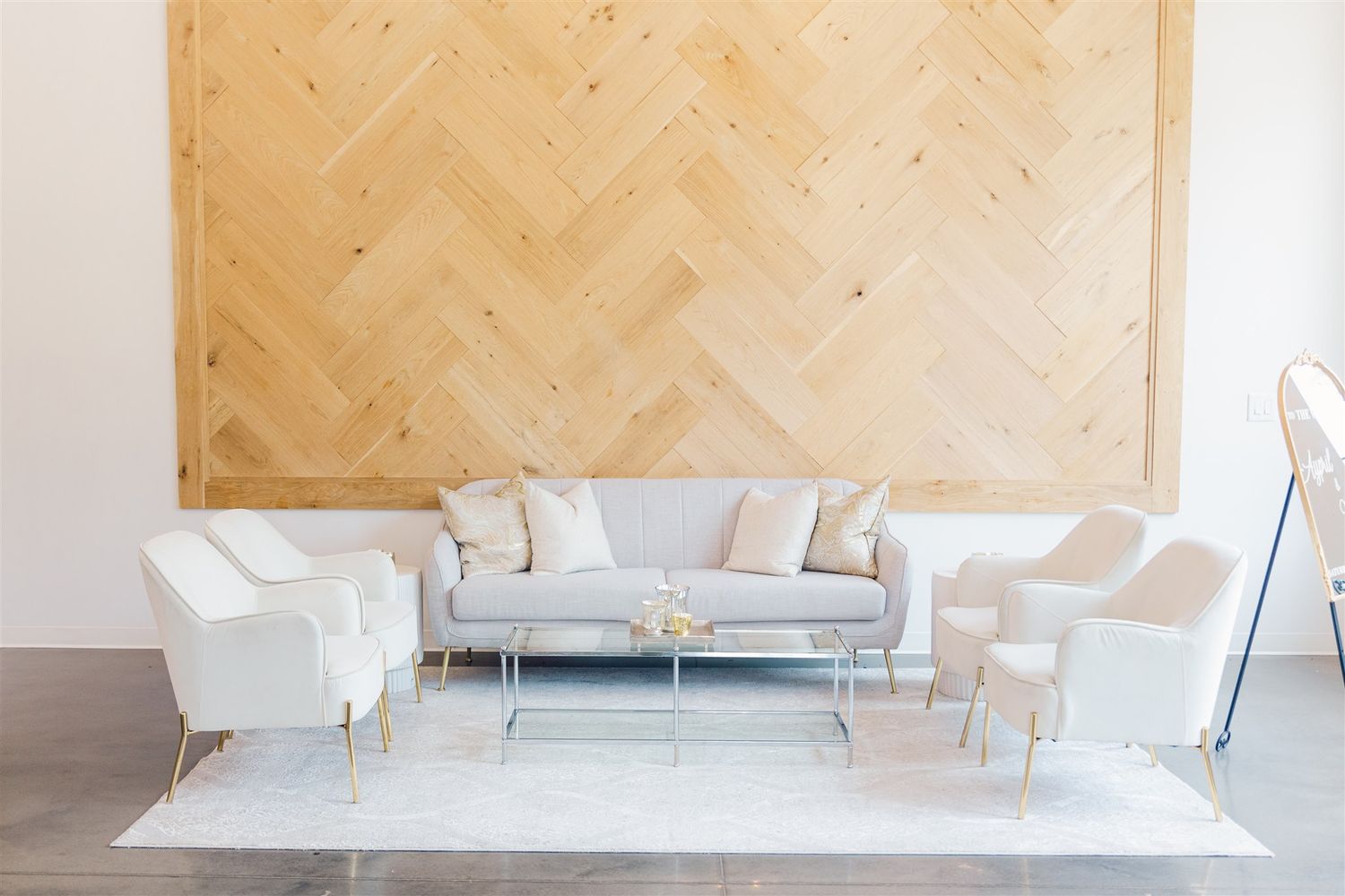 Modern white sofa with curved lines sits against a light wooden wall in a minimalist interior setting.