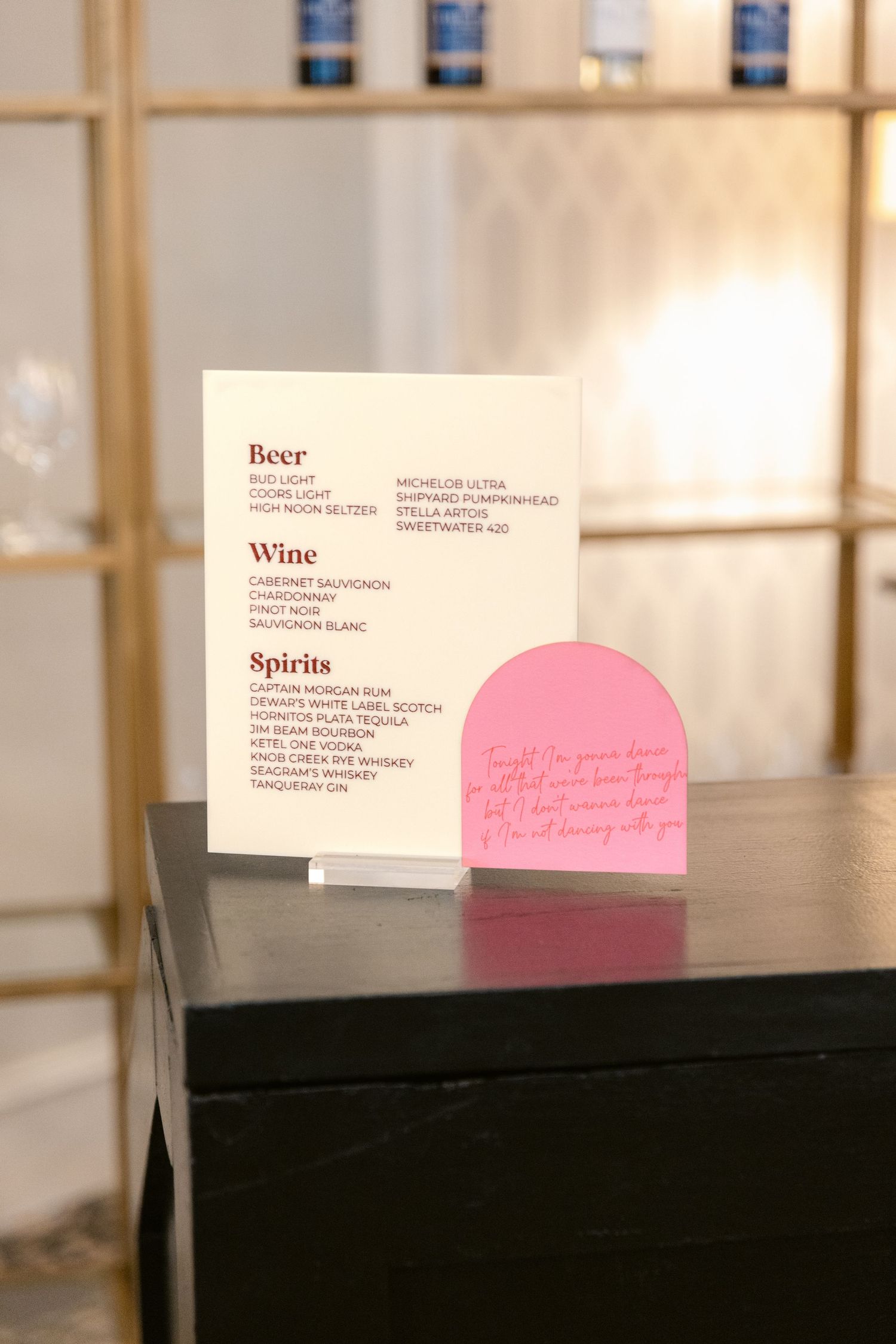 Menu cards and pink decor elements displayed on a dark surface in a restaurant setting.