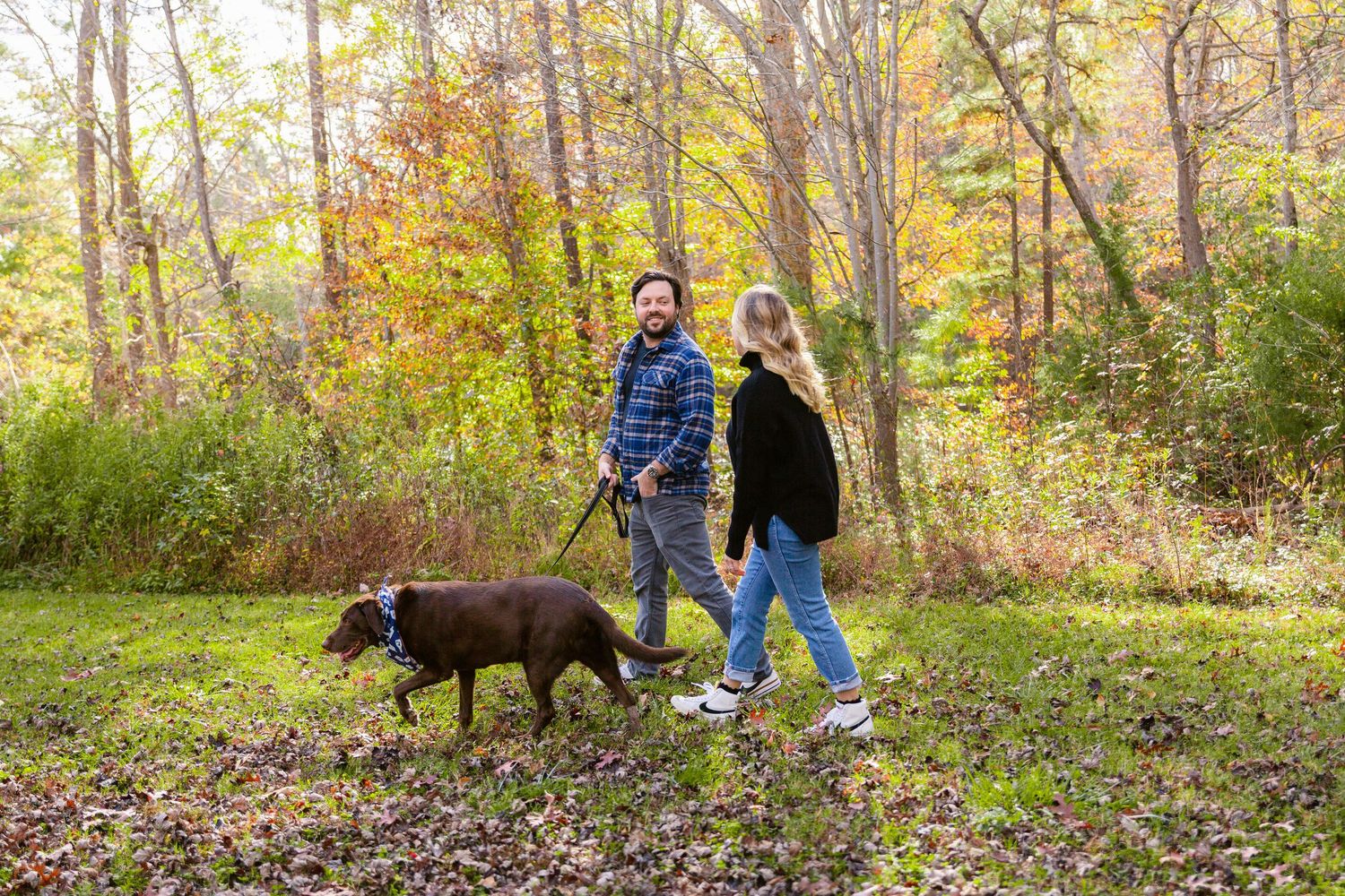 Family walking with their dog through a scenic fall forest trail.