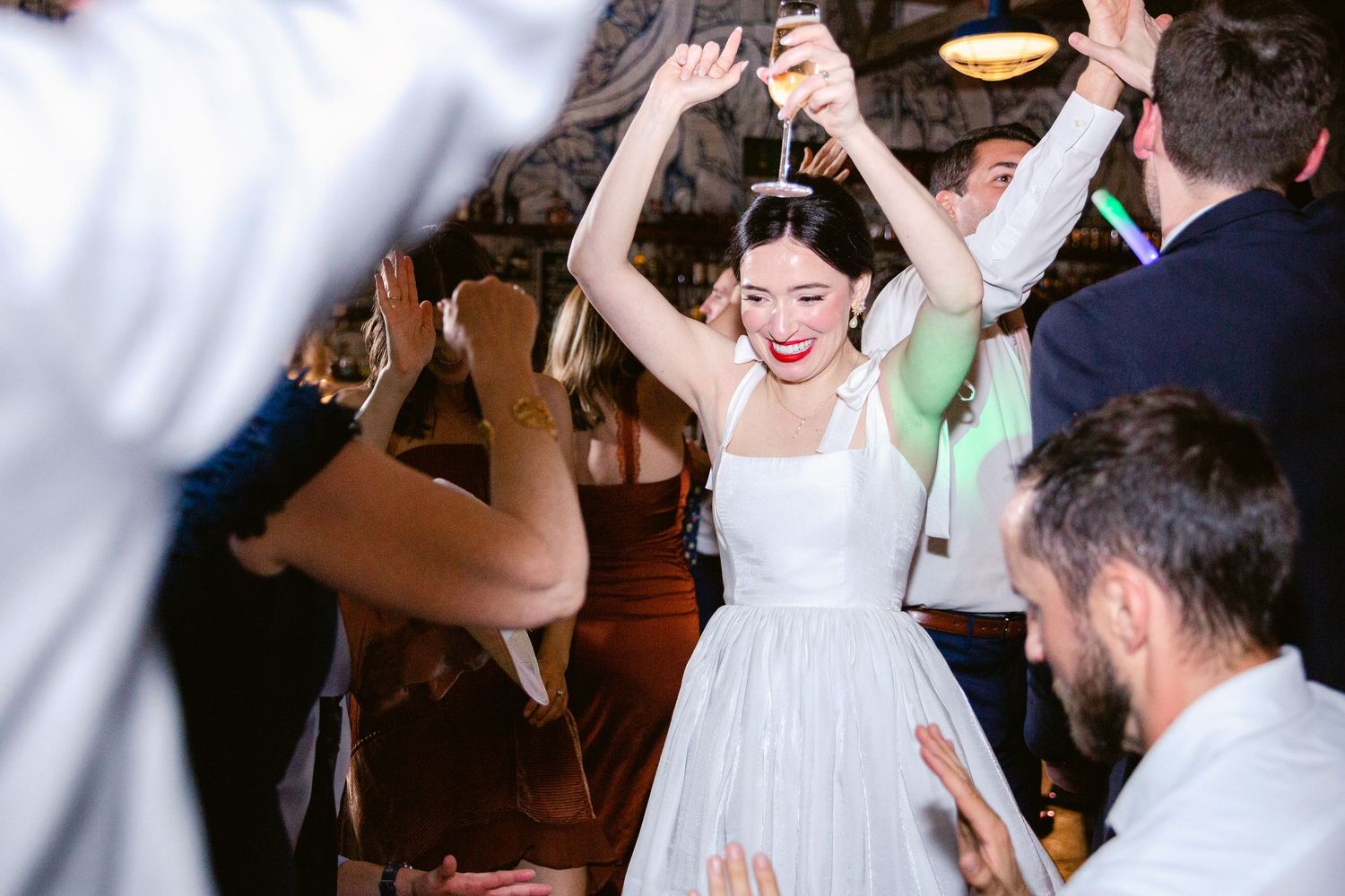 Wedding guests dance and celebrate together on a crowded dance floor at a lively reception party.